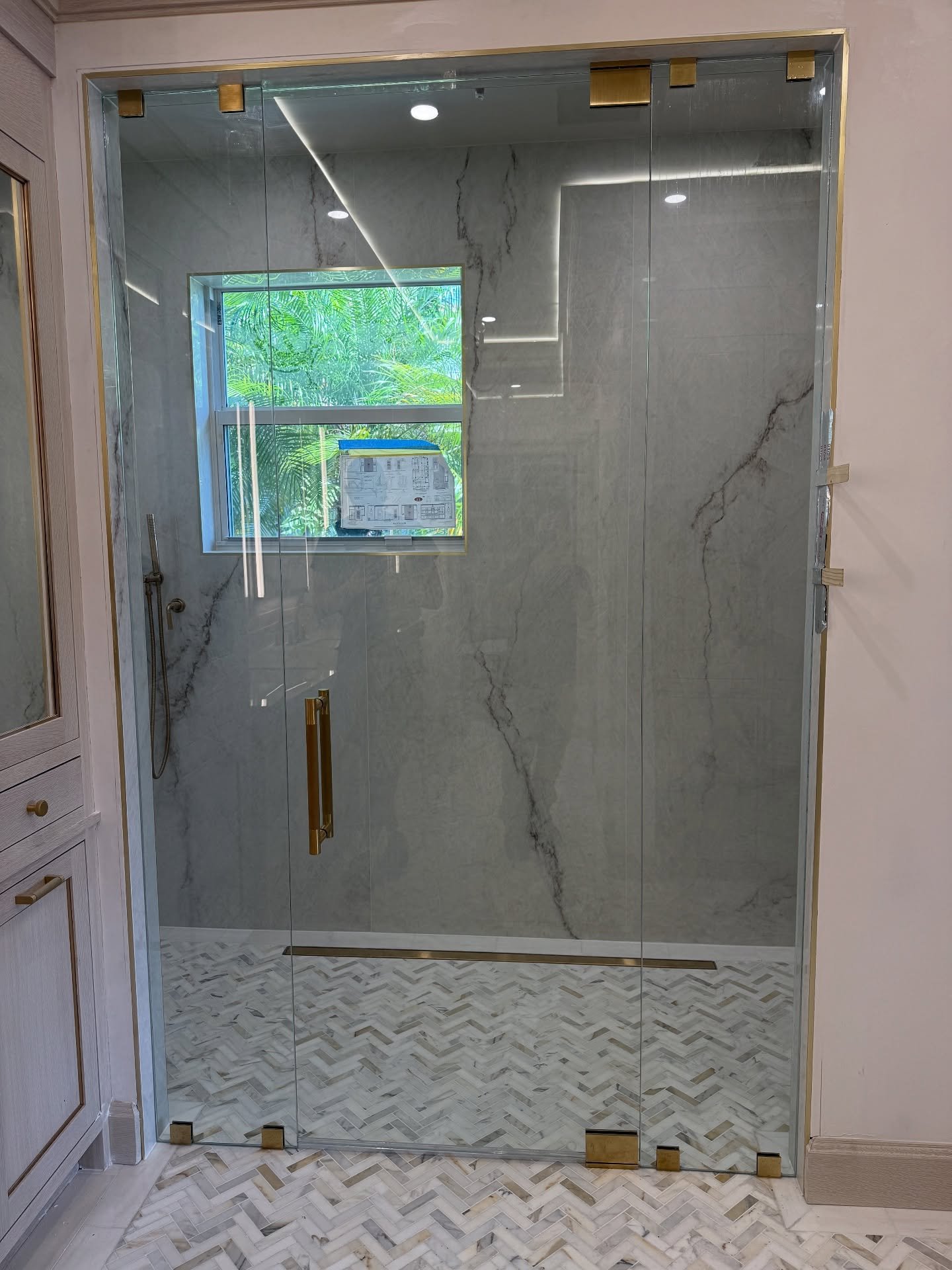 Frameless shower door and panel with gold hardware