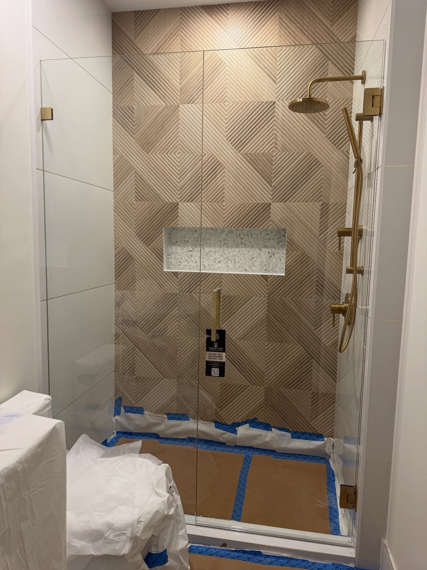 Frameless shower door beside geometric wall tile