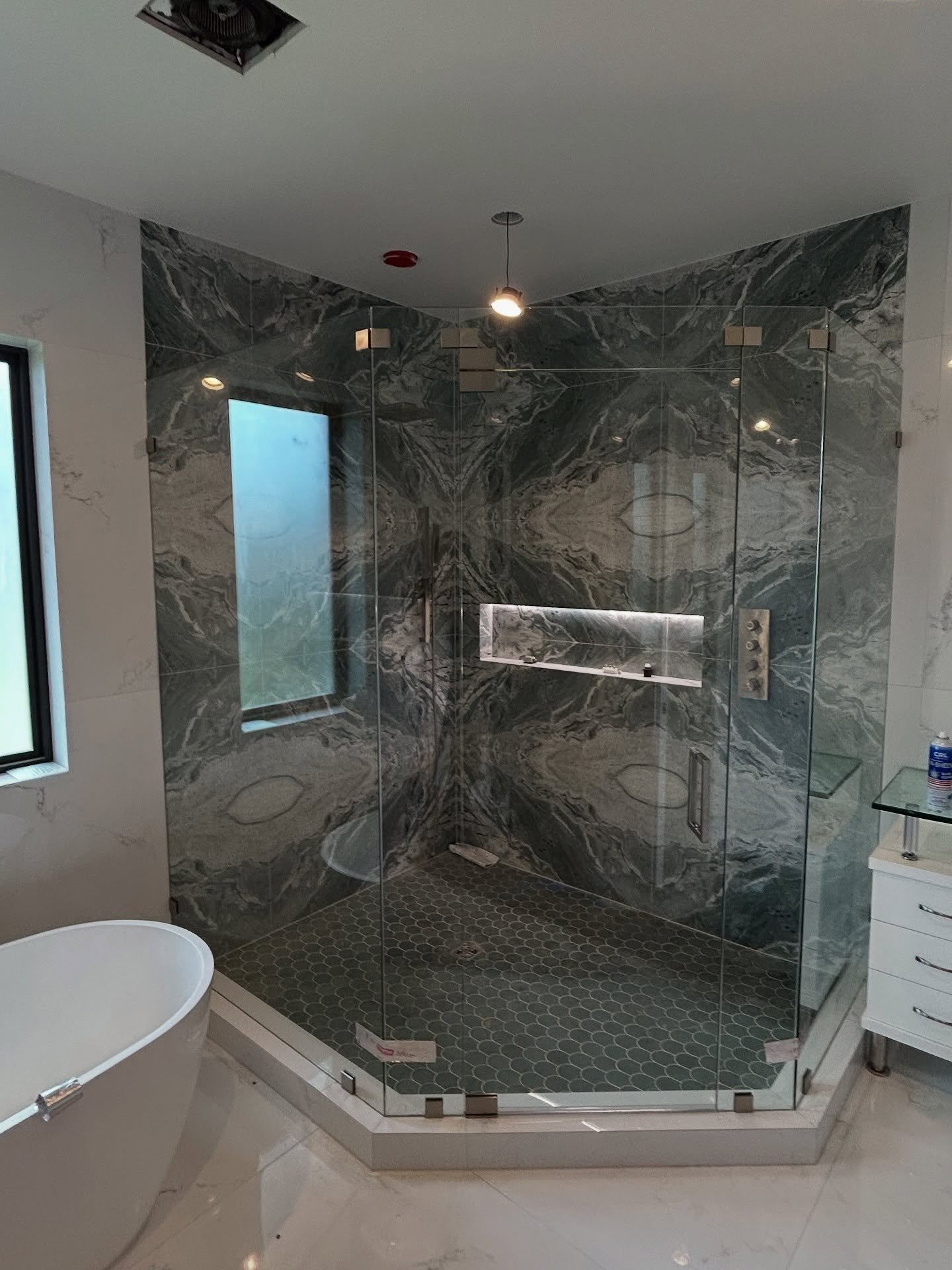 Neo-angle glass shower enclosure with patterned tile