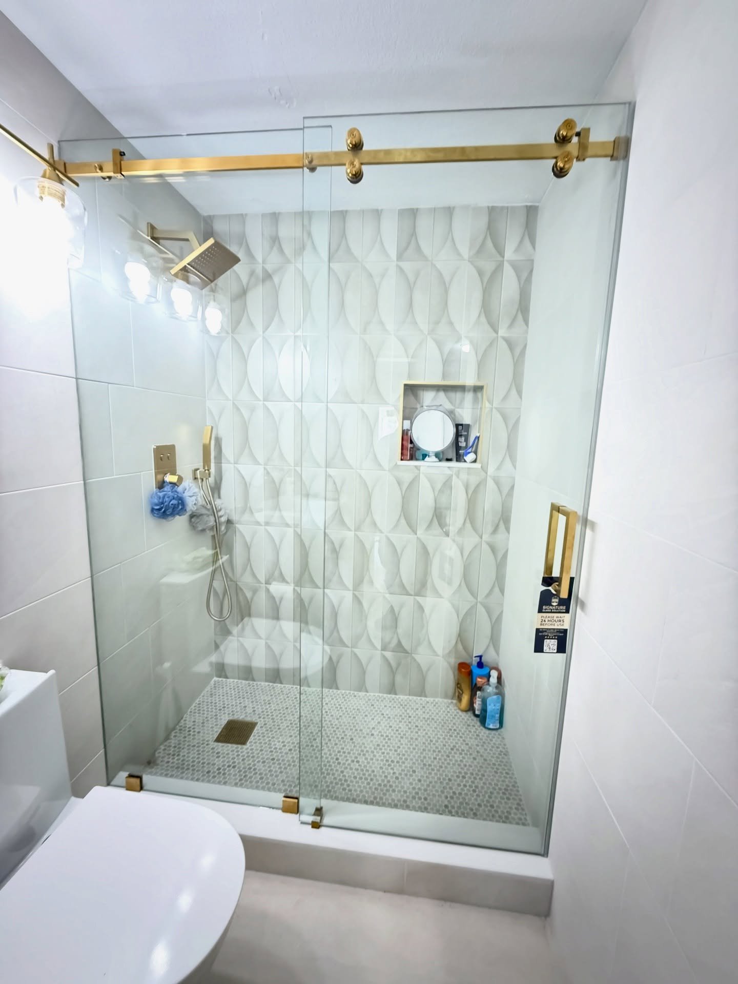 Sliding glass shower door with gold track and hardware