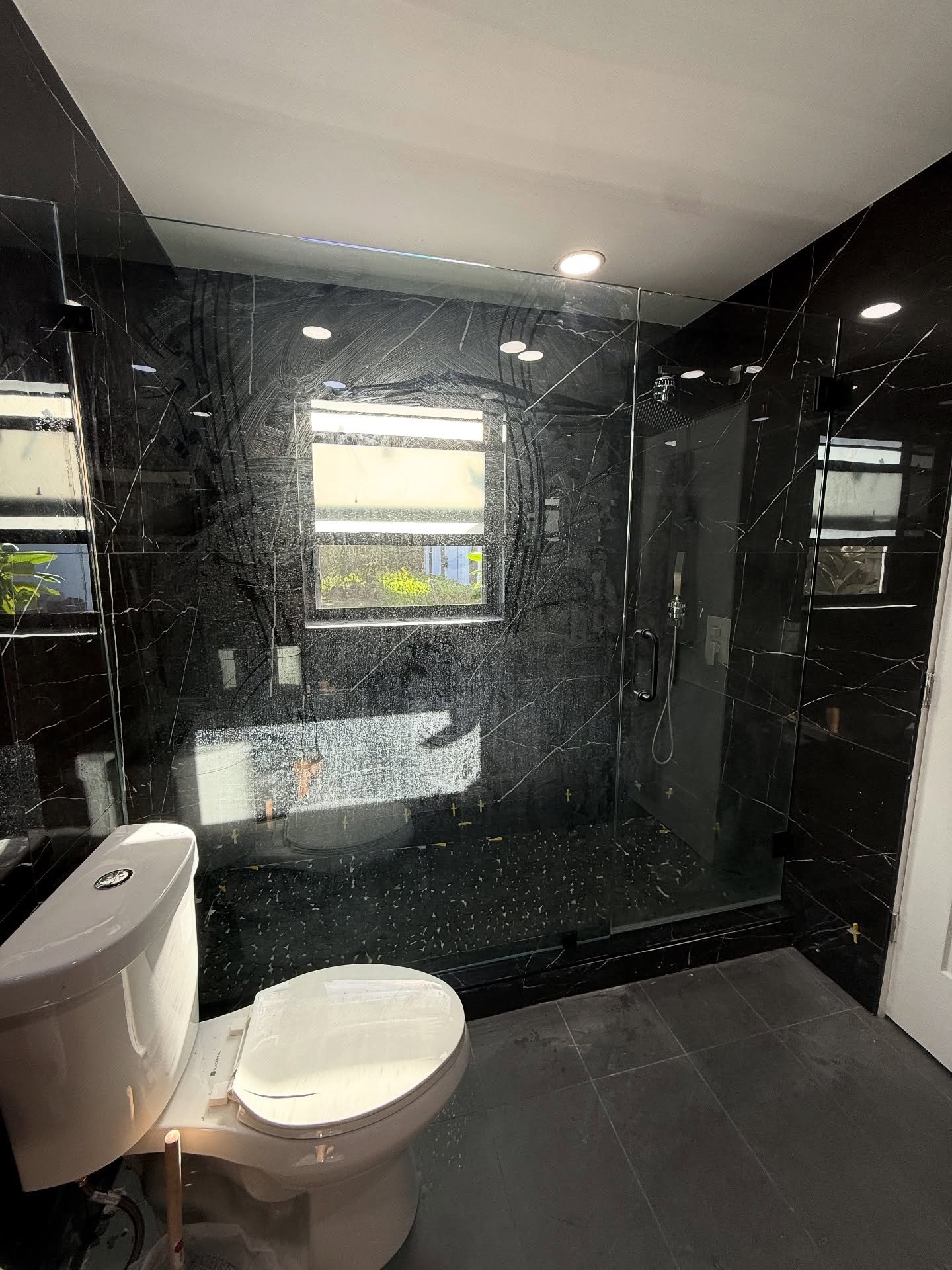 Frameless door and panel in a dark tiled bathroom